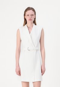 White sleeveless dress with a V-neck and belted waist. The fabric appears smooth, with a structured design and mid-thigh length.