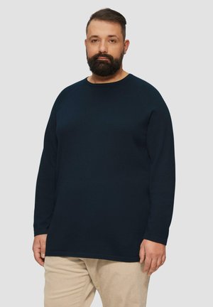 Marineblauwe sweatshirt met lange mouwen, gemaakt van een zachte, gestructureerde stof met een ronde hals en ribbelmanchetten, gecombineerd met lichtbeige ribfluwelen broek.