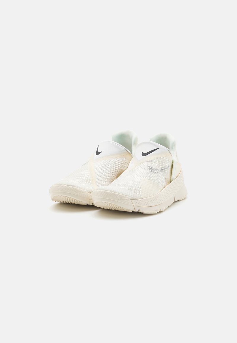 Baskets slip-on en mesh blanc avec une semelle lisse, présentant un logo Nike noir et un intérieur vert menthe clair.