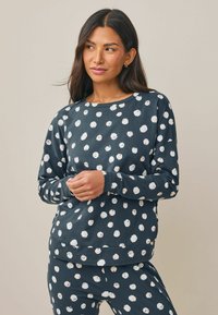 Mörkblå sweatshirt med vita prickar, långa ärmar, rund halsringning och avslappnad passform. Blandning av bomull med mjuk textur.