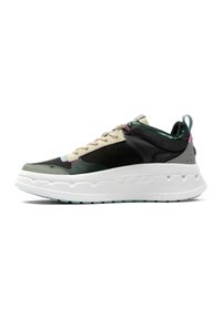 Sneakers con una toma nera e verde, accenti beige, materiali testurizzati e una suola bianca chunky. Presentano una chiusura con lacci e un'asola laterale.