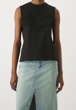 Schwarzes ärmelloses Top mit einem Chevron-Muster aus fransigem Stoff über der Brust; glatte Textur, runder Ausschnitt, kombiniert mit einem hellen Denim-Rock.