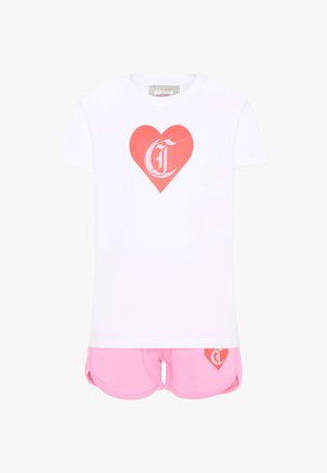 Camicia bianca a maniche corte con cuore rosso e lettera stilizzata, abbinata a pantaloncini rosa con dettaglio a cuore corrispondente sulla gamba sinistra.