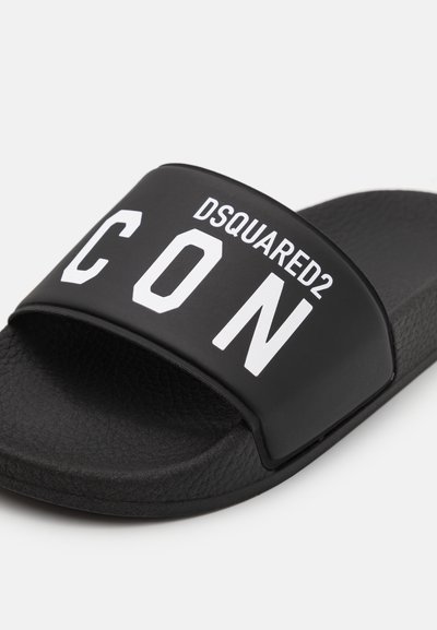 Schwarze Gummisandale mit strukturiertem Fußbett. Verfügt über einen breiten Riemen, der in großer weißer Schrift mit "DSQUARED2" und "CON" bedruckt ist.