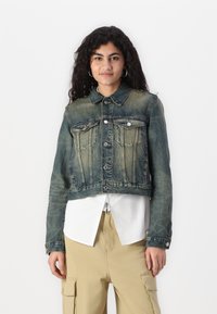 Giacca di jeans cropped in blu sbiadito con chiusura a bottoni, due tasche sul petto e un colletto classico. Tessuto strutturato con lievi dettagli di usura.