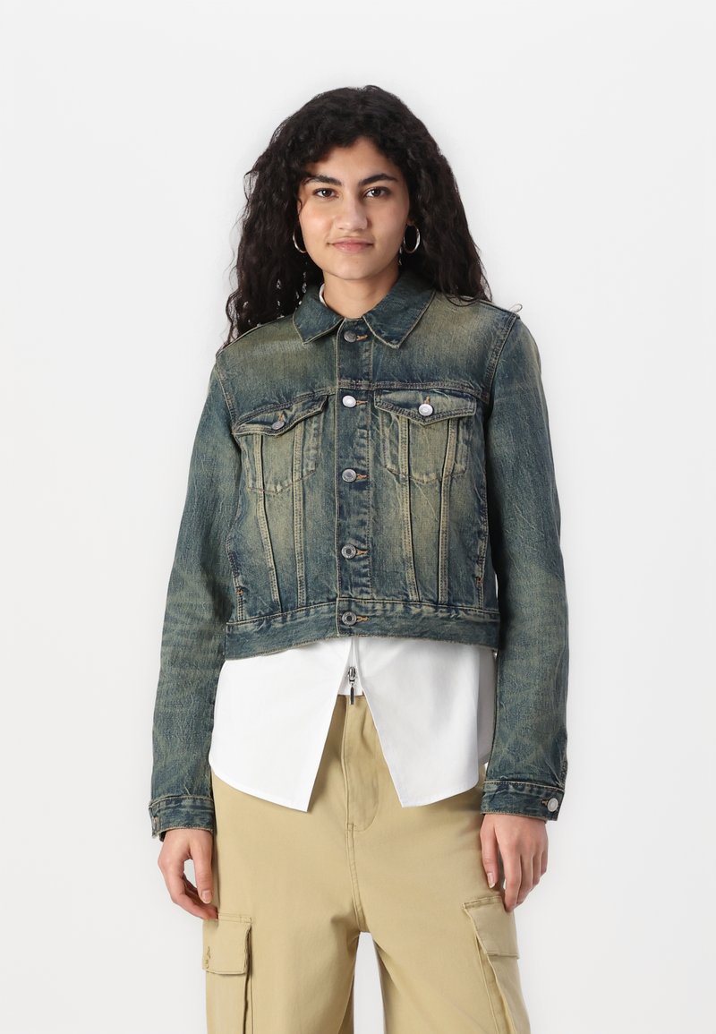 Giacca di jeans cropped in blu sbiadito con chiusura a bottoni, due tasche sul petto e un colletto classico. Tessuto strutturato con lievi dettagli di usura.