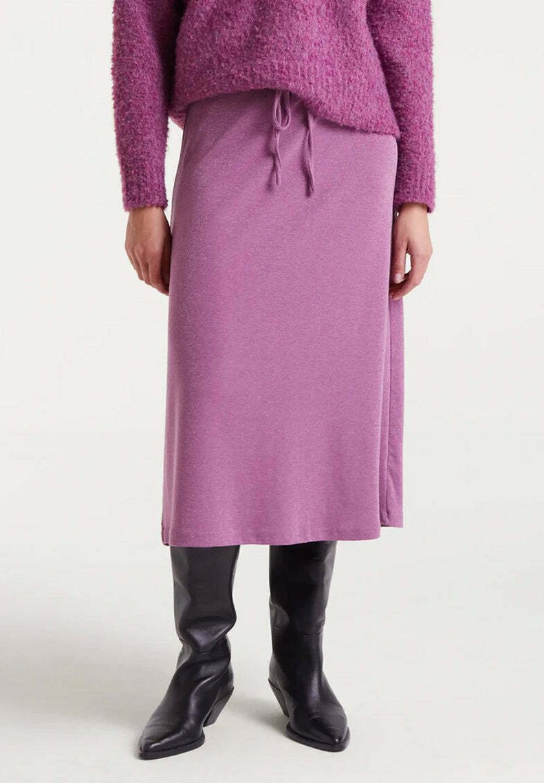 Falda morada de longitud media en tejido suave con cintura ajustable, combinada con elegantes botas negras hasta la rodilla. Top de punto texturizado en color rosa.