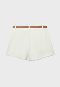 Short blanc sur mesure avec une ceinture marron passée dans la ceinture, sur un fond uni.