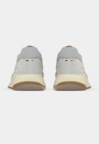 Ζευγάρι ανοιχτόγκρι και μπεζ αθλητικά παπούτσια, εμφανιζόμενα από πίσω, με υφασμάτινη υφή σε γκρι χρώμα και κρέμ σόλες, σε λευκό φόντο.