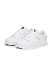 Baskets blanches en cuir avec une texture lisse, présentant un laçage à l'avant, un col rembourré et un accent avec logo sur la languette.