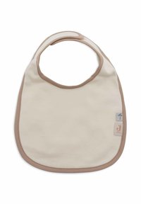 Bavoir beige avec une texture douce, des bords marron et une ouverture circulaire au niveau du cou. Présente de petites étiquettes de marque avec un logo d'arbre palmier et un "J".
