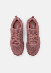 Des chaussures de sport rose clair avec une tige en mesh, un bout rond, une languette rembourrée et des lacets plats. Présente des motifs texturés sur les côtés et la semelle.