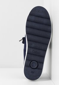 Suola di scarpa blu navy con gomma testurizzata, dotata di scanalature orizzontali e di un pad di presa circolare. "Gabor" impresso sul lato.