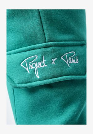 Fondo di felpa verde con una texture liscia, caratterizzato da testo ricamato bianco "Project x Paris" nella zona del petto.