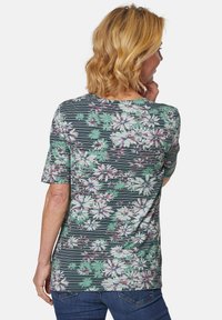 Groene en zwarte t-shirt met bloemenpatroon, korte mouwen, horizontale strepen en een ronde halslijn.