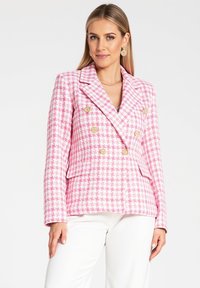 Różowo-biała, w kratę, dwurzędowa marynarka z złotymi guzikami i klapami; posiada dwie boczne kieszenie oraz fakturowany materiał.