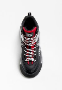 Mustahi ja valge kõrge toss, millel on punased aktsendid, tekstuuritud nahk ja mustrilised paelad. Omab pehmendatud kaelariba ja toetavat disaini.