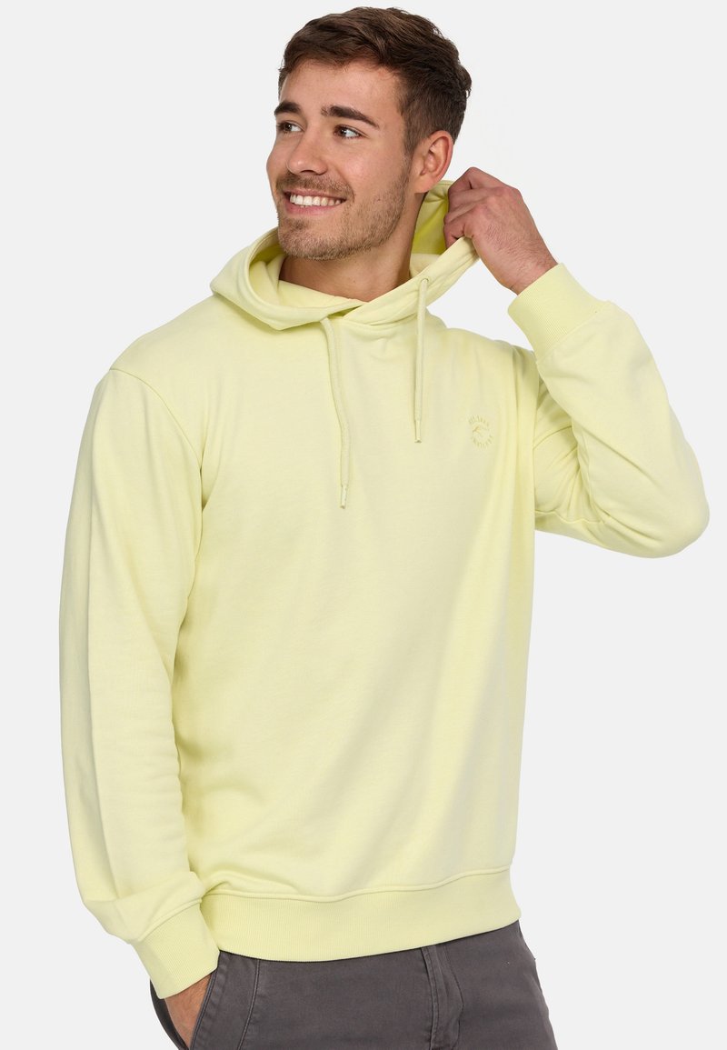 Sudadera amarilla claro hecha de un tejido suave, con capucha con cordones y un pequeño logo en el pecho. Corte estándar con puños de canalé.