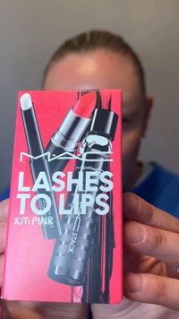 Person holder en rosa MAC Lashes to Lips sminkesettboks med illustrasjoner av leppestift, mascara og leppeblyant.