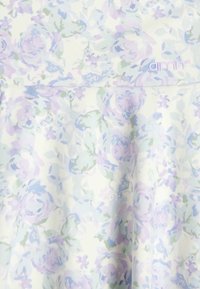 Blumengemustertes Stoffkleid in sanften Pastelltönen von Lavendel und Grün mit einer glatten Textur, Markenlogo am Ausschnitt.