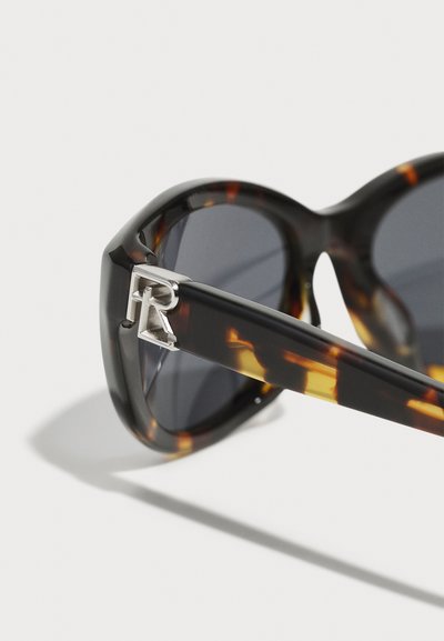 Ochelari de soare cu lentile întunecate din tortoishell, având un detaliu distinctiv în formă de "R" argintie pe bradă. Cadru robust cu un design elegant.