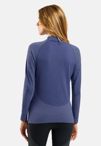 Langärmliges, tailliertes Oberteil aus strukturierter marinblauer Stoff. Merkmale einen hohen Kragen und kontrastierende Raglanärmel; nahtloses Design auf der Rückseite.