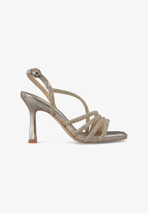 Sandal con tacco alto e strap in argento metallizzato con dettagli glitterati, punta aperta e tacco sottile e sagomato. Presenta una cinghia alla caviglia regolabile.