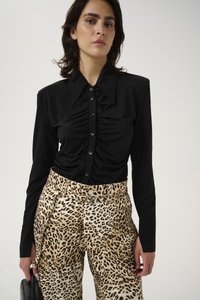 Zwart gerimpeld overhemd met lange mouwen, gecombineerd met tan kleurige hoge taille broek met panterprint en een bretelhals.