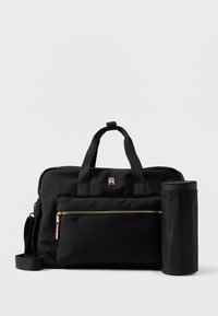 Saco de nylon preto com alças duplas, bolso frontal com fecho e hardware dourado. Inclui um estojo em forma cilíndrica preso ao lado.