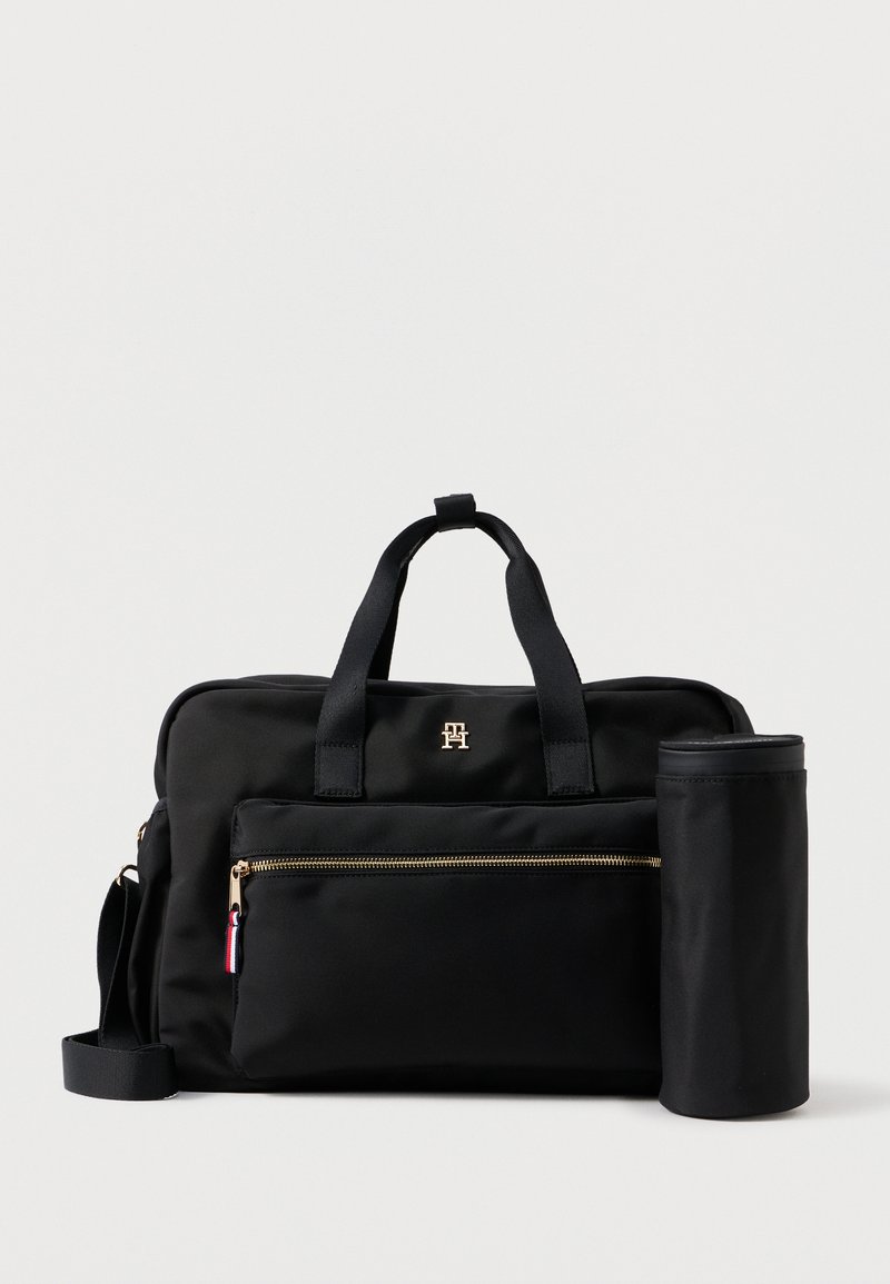 Saco de nylon preto com alças duplas, bolso frontal com fecho e hardware dourado. Inclui um estojo em forma cilíndrica preso ao lado.