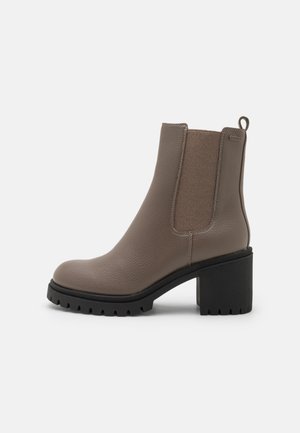 Brown leather ankle boot with elastic side panels, round toe, chunky black heel, and textured upper. Features a pull tab for easy wear.