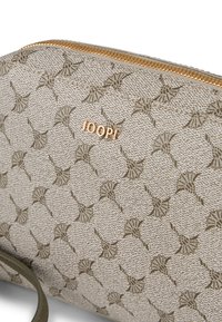Beige texturerad clutchväska med guldtonad dragkedja, som har ett upprepande mönster och en liten präglad logotyp "JOOP" på framsidan.