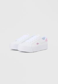 Λευκά αθλητικά παπούτσια με υφασμένη σόλα από καουτσούκ, επίπεδα λευκά κορδόνια, διακριτικές ροζ λεπτομέρειες στην φτέρνα και μικρό λογότυπο στο πλάι.