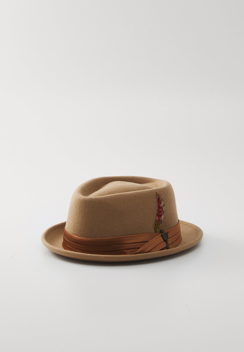 Wool felt hat, tan color, narrow brim, brown ribbon band, detailed with a feather accent, smooth texture, and round crown shape.