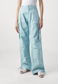Lichtblauwe cargo-broek met wijde pijpen, voorzien van meerdere zakken en een knoopsluiting. Gemaakt van een zachte, gestructureerde stof.