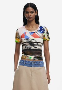 T-shirt à manches courtes avec un imprimé abstrait multicolore et un col rond, fabriqué dans un tissu doux. Associé à une jupe beige.