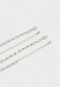 Three silver chain bracelets with lobster clasps and adjustable extension chains on a light background.