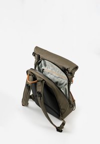 Zaino realizzato in tessuto verde oliva, con design a roll-top, spallacci regolabili e un interno grigio chiaro che presenta una tasca con zip.