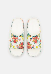 Sandales à semelle plate avec une base blanche, présentant un motif coloré de roses et de feuilles, une conception à bout ouvert et une semelle texturée.