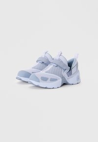 Light blue athletic shoes with mesh upper, padded collar, and rubber outsole. Features a strap closure and textured accents for support.