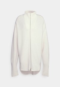 Sudadera con cremallera en suave tejido blanco, que presenta un cuello alto, detalles acanalados y un corte relajado con mangas largas y un dobladillo redondeado.