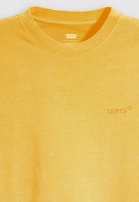 Geltona marškinėlių suapvalintu kaklu, pagaminti iš švelnaus medvilnės. Priekyje kairėje krūtinės pusėje yra išsiuvinėtas Levi's logotipas. Glotni tekstūra, kasdieniška siluetas.