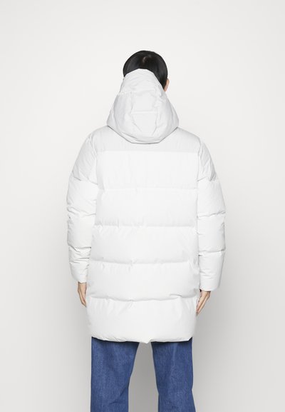 Doudoune blanche avec capuche, dotée de sections cousues horizontalement et de manches longues. Texture lisse avec une coupe décontractée.