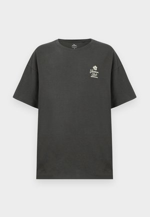 Melnas kokvilnas T-krekls ar īsām piedurknēm, brīvs piegriezums un mazs balts attēls, kas lasāms "Brīvdienu klubs" kreisajā krūtīs.