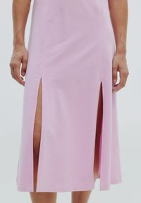 Rosa Baumwollkleid mit seitlichen Schlitzen, gerader Schnitt und sauberer Naht. Glatte Textur mit einem lässigen Design.