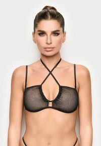 Reggiseno in rete nera con scollatura profonda, spalline incrociate e dettagli decorativi a ruffles lungo il bordo. Design minimalista.