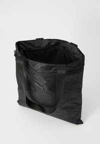 Czarna torba na ramię z wzorzystym materiałem i logo Puma, wyposażona w dwa mocne uchwyty oraz otwartą górę, z widocznym wnętrzem.