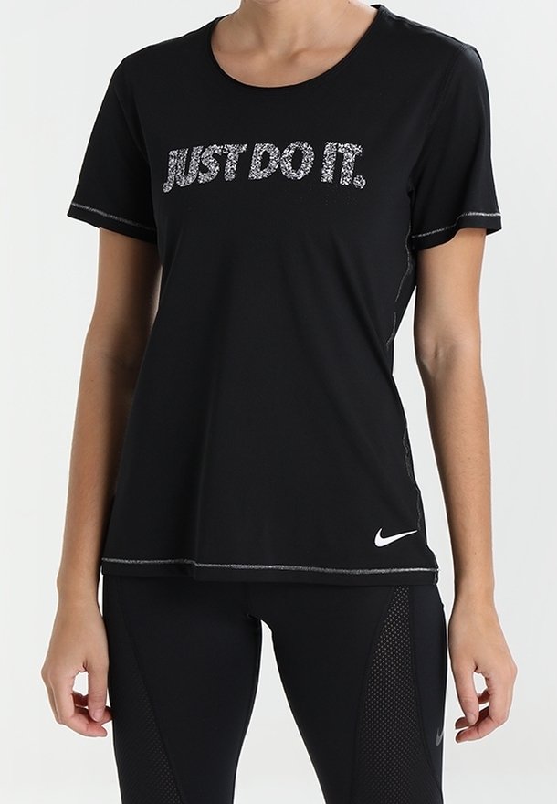 Kvinna klädd i en svart Nike-t-shirt med texten "JUST DO IT." och svarta träningsleggings med nätpaneler.