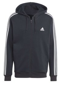 Felpa con cappuccio nera con zip realizzata in tessuto morbido, con cappuccio regolabile tramite coulisse, dettagli a tre strisce bianche sulle maniche e logo Adidas sul petto.