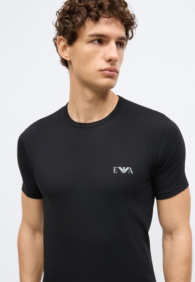 Black cotton t-shirt featuring a round neckline and a small white logo on the left side. Classic fit with short sleeves. Smooth texture.